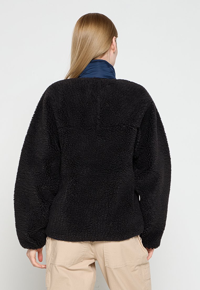 Schwarze Fleecejacke mit einer strukturierten, weichen Oberfläche. Verfügt über einen lockeren Schnitt und einen hohen Kragen. Die Rückansicht zeigt keine sichtbaren Verschlüsse.