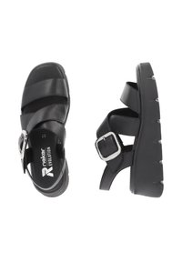 Sandales noires en cuir avec de larges brides croisées, une fermeture à boucle sur le côté et une semelle plateforme épaisse avec des crampons prononcés.