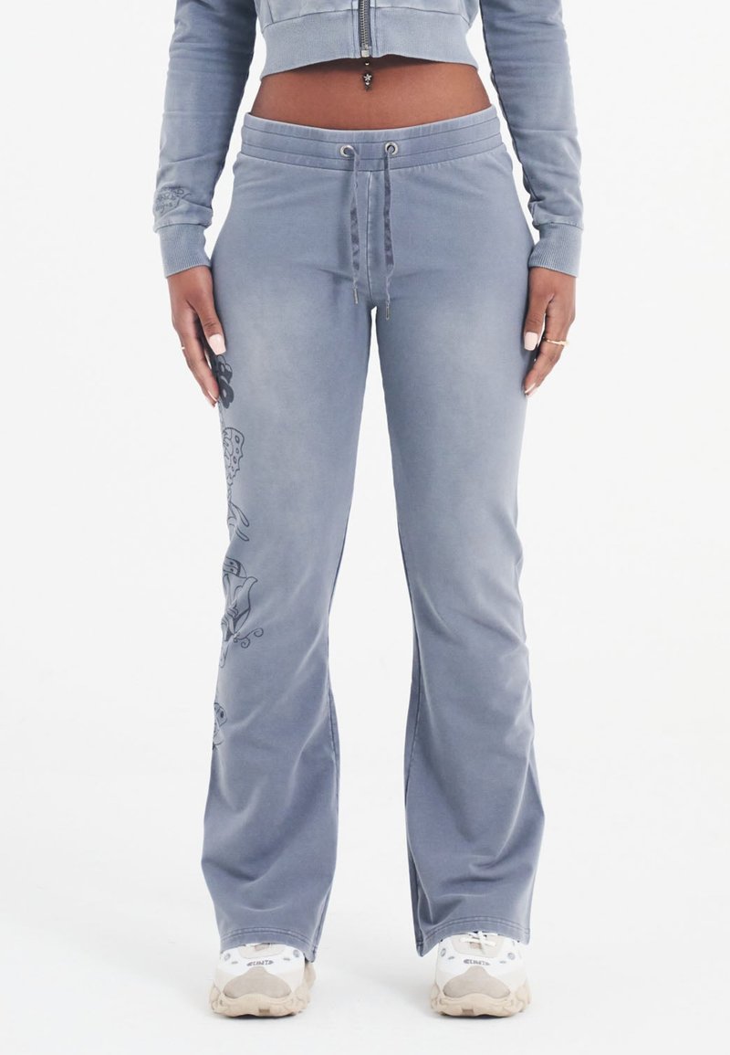 Lichtblauwe joggingbroek met een relaxte pasvorm, een koordsluiting in de taille en bloemgraphic accenten aan de zijkant. Zachte stof met een lichte glans.