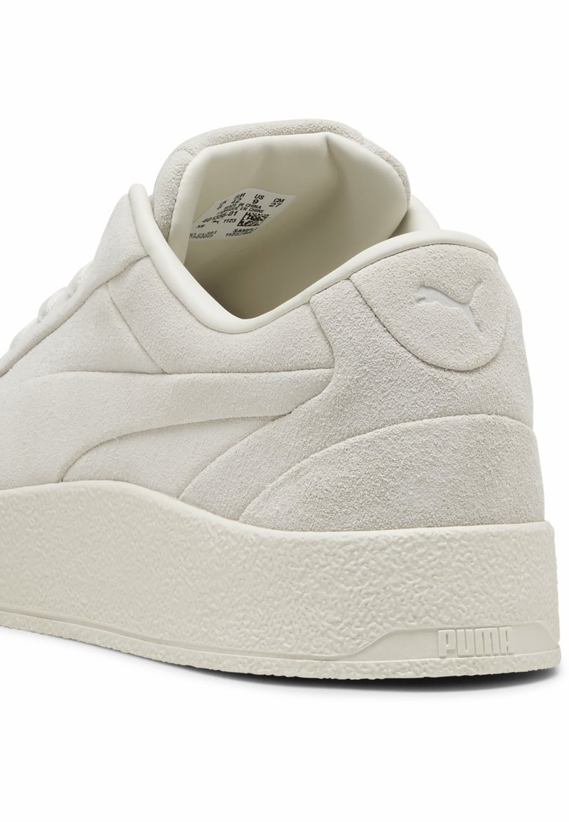 Sneaker bianco in suede con tacco testurizzato e suola in gomma. Presenta un logo in rilievo sul tacco e un colletto liscio e arrotondato.