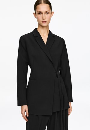 Czarna, dopasowana marynarka z kopertowym zapięciem, długimi rękawami i wiązaniem w talii. Posiada jedną kieszeń na piersi oraz czyste, proste linie.