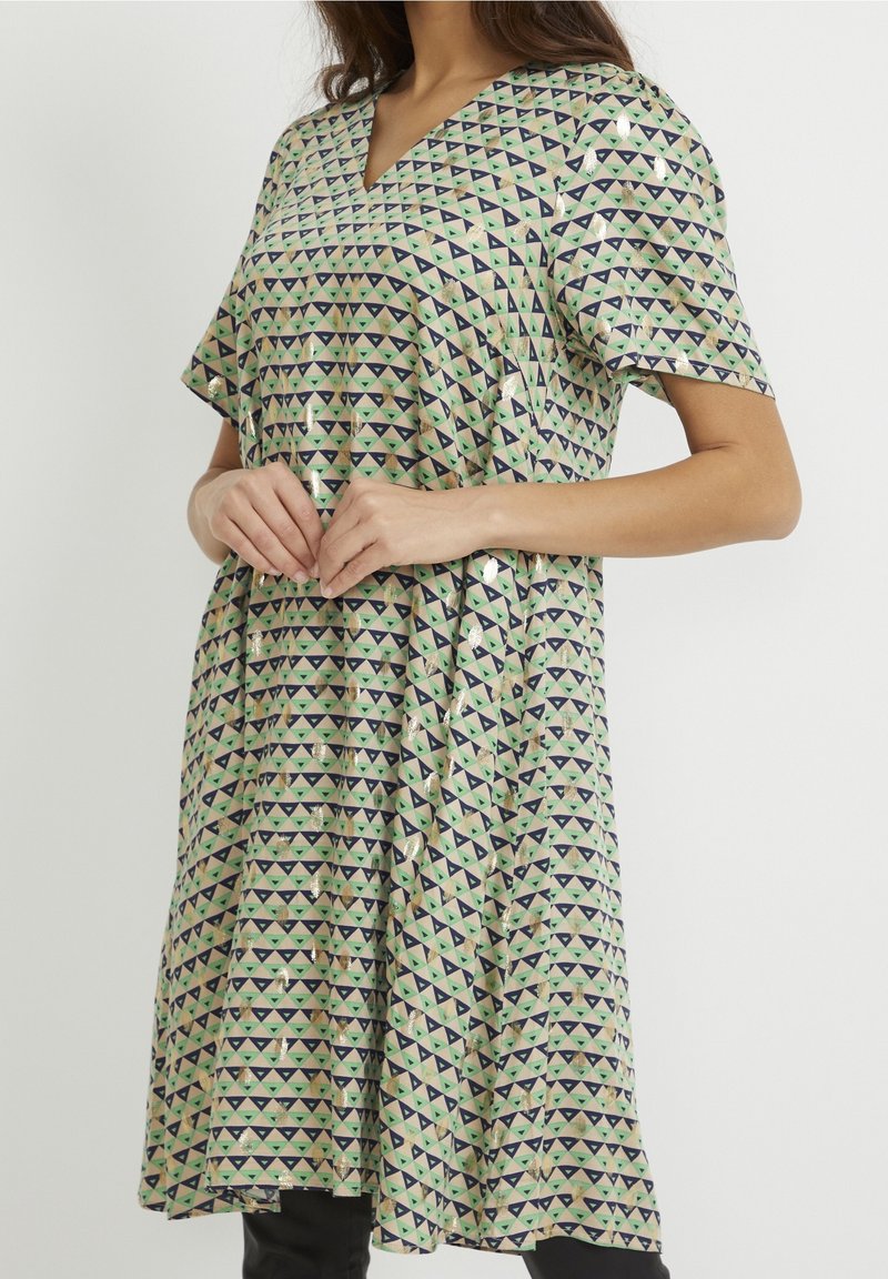 Grön och beige klänning med V-ringning, korta ärmar och ett geometriskt triangelmönster i marinblått och mintgrönt med glänsande detaljer.