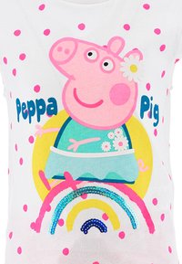 Weißes Stoff-T-Shirt mit einem großen rosa Cartoon-Schwein mit einer Blume, buntem Regenbogen und rosa Punkten. Text "Peppa Pig" in Blau gedruckt.