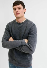 Grijze katoen sweatshirt met ronde hals en lange mouwen. Subtiele vervaagde textuur, geribde cuffs en zoom, met een klein logo tag aan de onderkant.