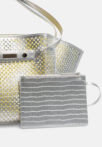 Zilveren geperforeerde totebag met gele accenten en een bijpassende zilveren pouch met krokodillenstructuur, met een gladde afwerking en dubbele handvatten.