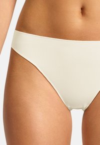 Parte inferiore di bikini color beige chiaro, realizzata in tessuto morbido, presenta una vita bassa e copertura minima. Bordo senza cuciture per un fit elegante.