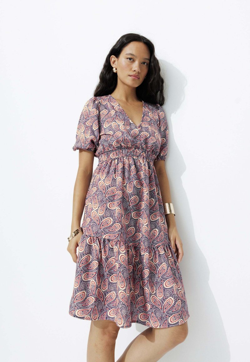 Robe à imprimé paisley violet avec des manches courtes bouffantes, un décolleté en V et une taille froncée, dotée d'une jupe à niveaux et d'une texture de tissu douce.