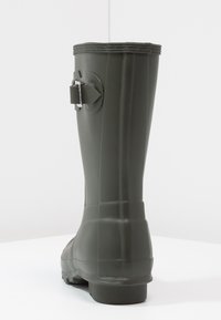 Grüner gummi wasserfester Stiefel mit rundem Schaft, hinterem Schnallenverschluss, strukturiertem Oberflächenmaterial und einer stabilen, gemusterten Sohle. Seitliche Nahtdetails sichtbar.