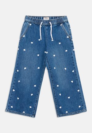 Pantalon large en denim bleu avec des motifs de cœurs blancs et une taille élastique avec des cordons blancs.