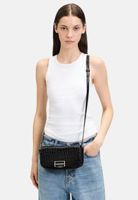 Schwarze, krokodil-embossierte Leder-Crossbody-Tasche mit einer silbernen Schnalle. Kompaktes Design, verstellbarer Tragegurt, glatte Textur, minimaler Hardware.