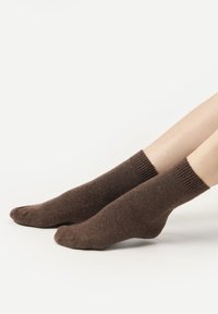 Chaussettes en coton marron avec des bords côtelés, présentant une texture douce et un design mi-mollet, présentées sur un fond neutre.