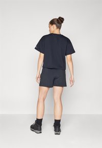 Camiseta negra de algodón de manga corta combinada con pantalones cortos oscuros a juego. El conjunto presenta un corte relajado y un diseño simple y limpio.