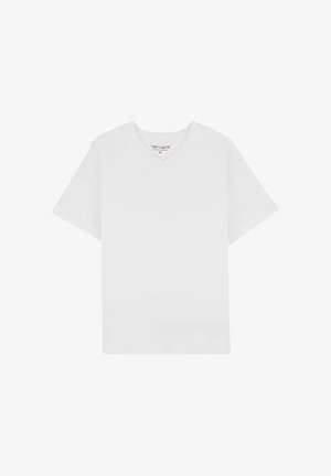 T-shirt blanc uni à manches courtes avec col en V, étalé à plat avec l'étiquette du col visible, sur un fond blanc.