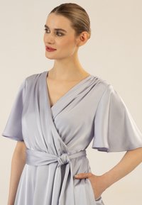 Lavendelfarbenes Wickelkleid aus glattem Satin, mit kurzen Ärmeln, einem geknoteten Taillengurt und einem V-Ausschnitt.