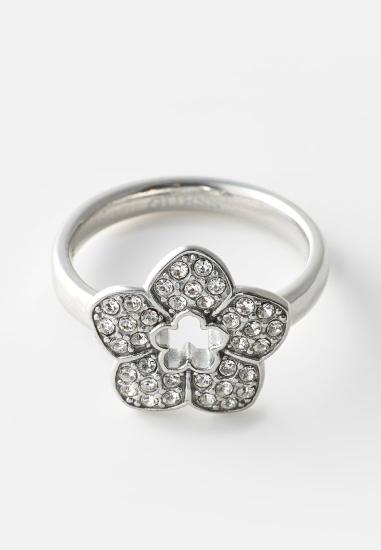 Anillo de plata con un diseño en forma de flor incrustado con pequeños cristales claros sobre un fondo blanco uniforme.