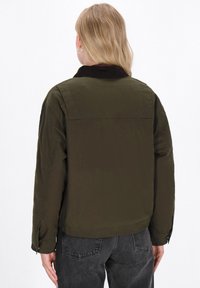 Olijfgroen bomberjack met een corduroy kraag, verlaagde schouders en een casual pasvorm. Bevat een soepele textuur en elastische manchetten.