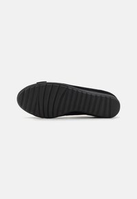 Suola di scarpa in gomma nera con un motivo scanalato per la trazione. Presenta una texture liscia e opaca e un tacco leggermente elevato.