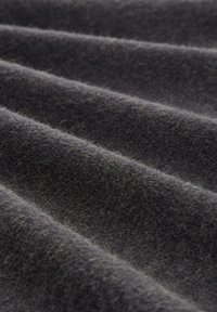 Tissu en laine gris foncé avec une surface douce et texturée, présentant des variations subtiles et de légers plis créant un aspect ondulé.