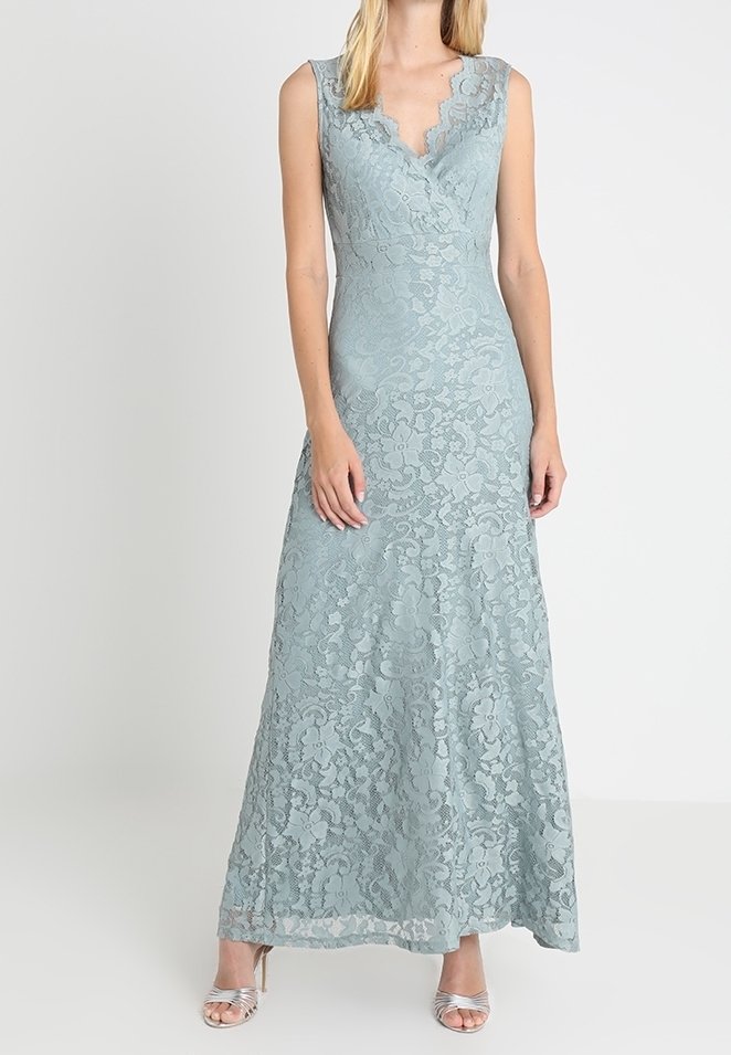 Robe de soirée en dentelle bleu pâle sans manches avec un col en V festonné, taille ajustée et jupe longue évasée portée avec des talons argentés.