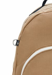 Bruine stof rugzak met witte accenten, ronde vorm, gestructureerd oppervlak en een klein logo-label met een ring aan de zijkant.