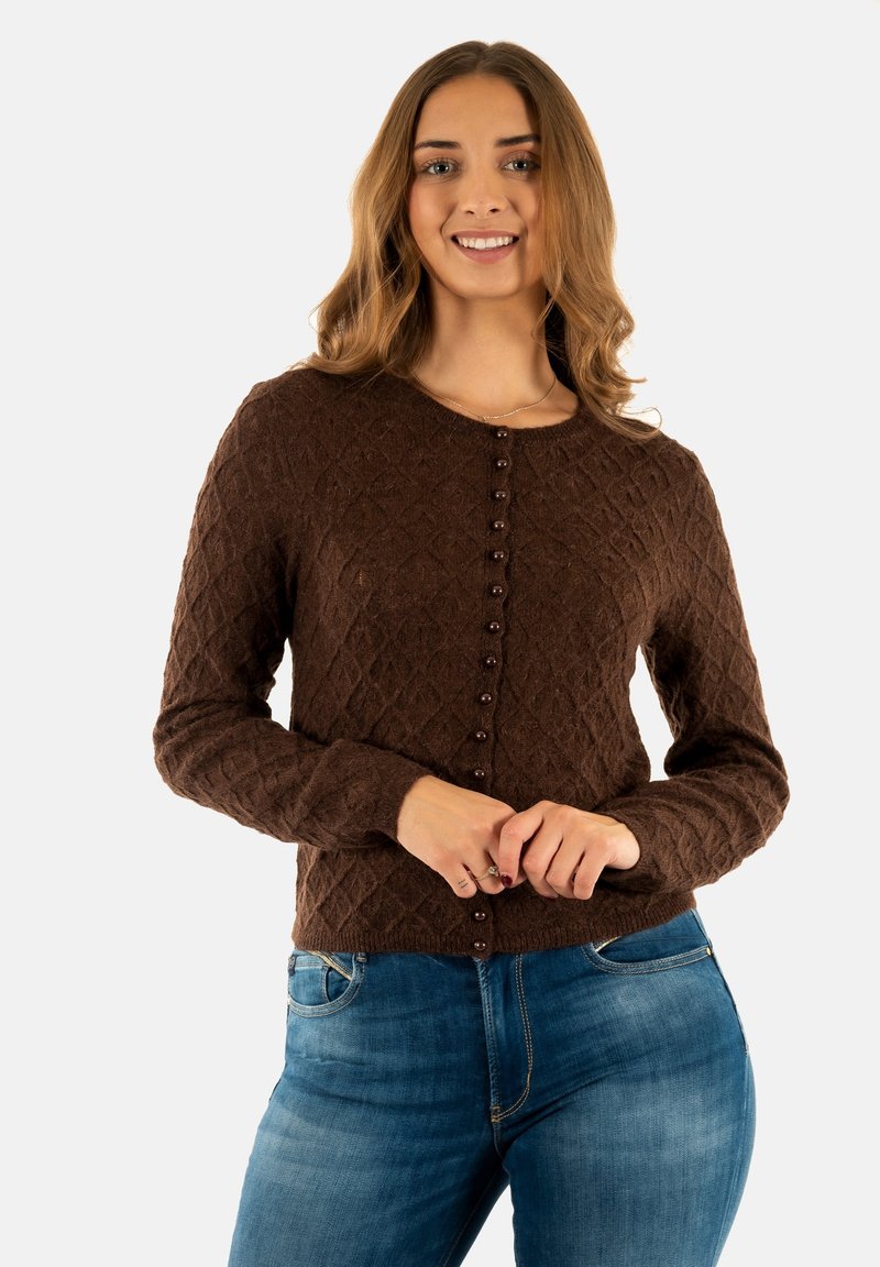 Bruine gebreide cardigan met een ruitpatroon, ronde halslijn en knoopsluitingen aan de voorkant. Draagt over een blauwe jeans.