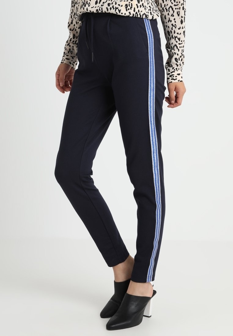 Navy slim-fit kalhoty s modro-bílými pruhovanými bočními panely, elastickým pasem a měkkou tkaninou; spárovány s černými podpatkovými mules.