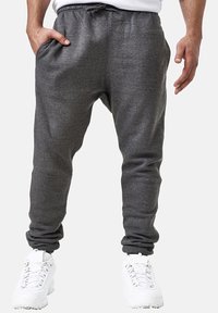 Gray cotton blend joggers with an elastic waistband, side pockets, and tapered cuffs, paired with white athletic shoes.