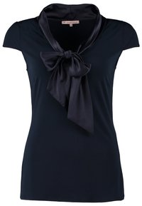 Blouse noire à manches courtes avec col en satin brillant et grand nœud noué à l’encolure, taille ajustée, sans boutons visibles ni motifs.