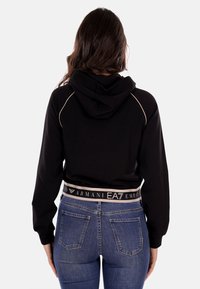 Felpa nera con cappuccio dal design cropped, con un orlo a contrasto etichettato "EA7 Emporio Armani" e cuciture leggere a contrasto.