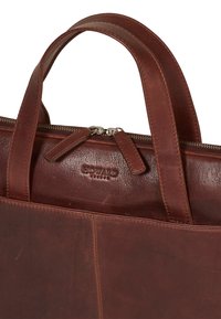 Borsa a mano in pelle marrone con due manici arrotondati, chiusura con zip, logo impresso e texture liscia. Design semplice senza motivi visibili.