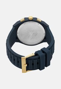 Nautički silikonski remen za sat s zlatnim metalnim dijelovima, s teksturiranim dizajnom i višestrukim žljebovima. Kućište od nehrđajućeg čelika, okruglog oblika.