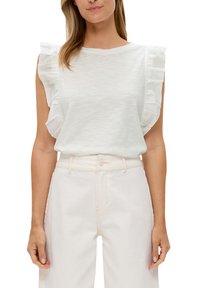 Biała bezrękawnik z falbaniastymi akcentami na ramionach; miękki, lekki materiał; w połączeniu z jasnymi spodniami z wysokim stanem.