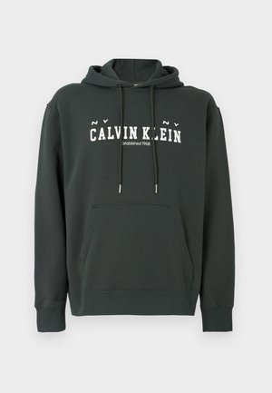 Musta vihreä puuvillahuppari, jossa on kenguru-tasku, nauhakuusi ja valkoinen "CALVIN KLEIN" -logo. Varustettu ribattuja hihansuita ja helmaa.