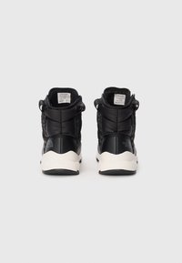 Black high-top sneakers with padded texture, featuring a white rubber sole and branded accents on the heel. Rear view shows laces and collar detail.