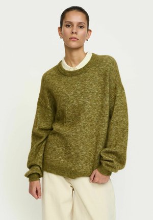 Veľký zelený sveter vyrobený z mäkkej, textúrovanej látky. Má okrúhly výstrih, dlhé rukávy a rebrované manžety aj lem.