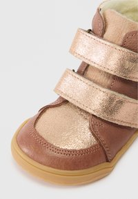 Ruda ir metalizuota rožių auksinė vaikų batai su dviem Velcro diržais ir guminiu padu, viduje turintys minkštą pūkuotą pamušalą.