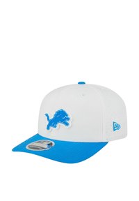 Casquette de baseball blanche et bleue avec un logo de lion bleu à l'avant et le logo New Era sur le côté, affichant un autocollant noir et blanc sur la visière bleue.