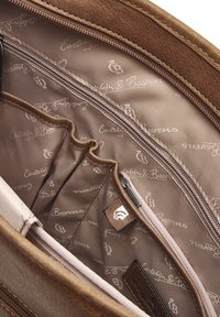 Das Innere der braunen Ledertasche verfügt über eine glatte, hellbeige Futterung mit einem sich wiederholenden Logomuster, einem Reißverschlussfach und mehreren Aufbewahrungsfächern.
