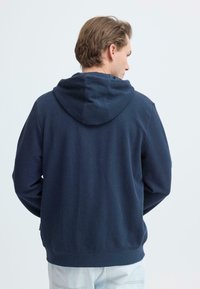 Sweat à capuche bleu marine avec une finition texturée, équipé d'une capuche avec cordon de serrage, de manches longues et d'un ourlet côtelé. Vue de dos illustrant la simplicité du design.