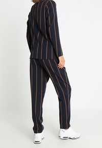 Niebiesko-brązowy zestaw odzieży domowej w paski, składający się z długiego rękawa bluzki oraz pasujących spodni, oba w luźnym kroju i z teksturowanej tkaniny.