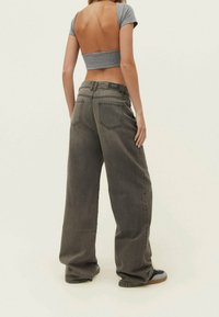 Top corto gris con mangas cortas, combinado con jeans sueltos de color gris oscuro con bolsillos traseros y un diseño de pierna recta.