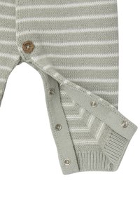 Hellgrüner gestrickter Overall mit weißen Streifen, ausgestattet mit einem Holzknopf und metallenen Druckknöpfen, gerippten Bündchen und strukturiertem Stoff.