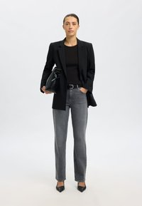 Fekete blézer, testhez álló fekete felső, szürke egyenes szárú farmernadrág és hegyes orrú fekete magassarkúk. Egy fogantyús, sima felületű fekete táskát tartott.