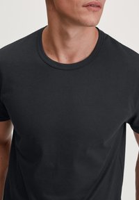 Donkergrijs t-shirt met korte mouwen, gemaakt van zachte katoen. Heeft een ronde halslijn en een gladde textuur. Geen zichtbare patronen of afbeeldingen.