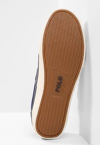 Podešev boty s texturovaným gumovým povrchem, v hnědé barvě s béžovými akcenty a vyraženým logem "POLO". Hladké hrany a minimalistický design.