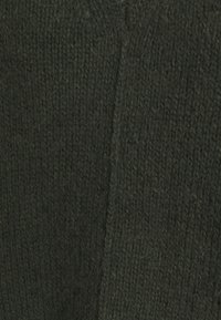 Mörkgrön stickad tyg med synlig ribbad textur och mjuka fluffiga fibrer.