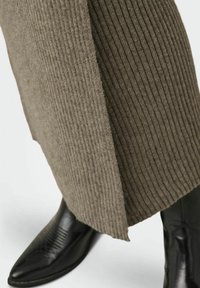 Falda de punto gris con canalé y abertura lateral, combinada con botines de cuero negro de punta en featuring detalle de costura diagonal.