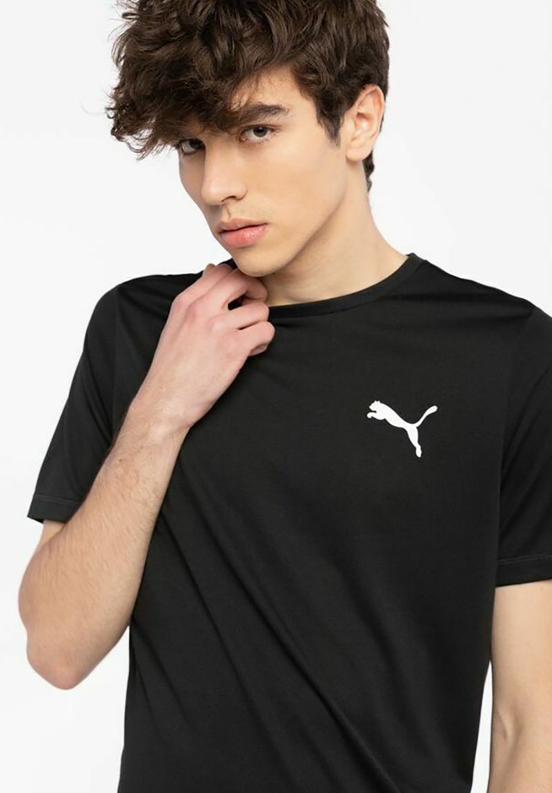 Sort T-shirt lavet af glat stof med et hvidt Puma-logo på venstre bryst. Korte ærmer og rund halsudskæring.