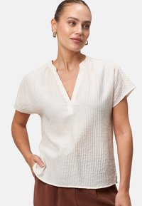 Blusa bianca a maniche corte con scollo a V, in tessuto strutturato caratterizzato da sottili righe verticali e una vestibilità comoda.