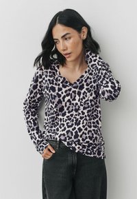 Bluză cu mânecă lungă, imprimată cu leopard, în violet și negru, cu decolteu în V și croi lejer. Fabricată dintr-un material moale și ușor.